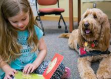 Child reading to therapy dog at Macon County Public Library